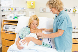 New mom being taught how to breastfeed by nurse